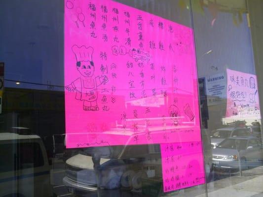 Hand written pink sheet menu taped on their window.