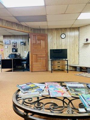 Inside waiting room with magazines, fire place, large tables and nice couches