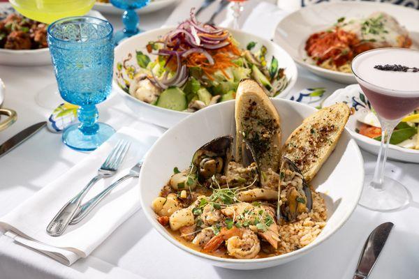 A spread of dishes for dinner service including Cioppino