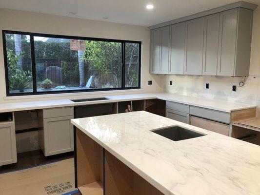 The finished marble island countertop with surrounding quartz surfaces