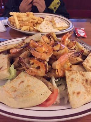 Plato Mixto mediano. Beef,Chicken & shrimp over a salad. Pupusas included. Other plate is a kids quesadilla w/ french fries.