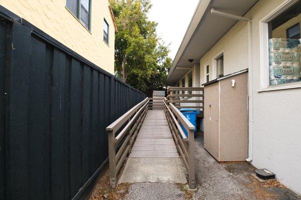 Ramp for wheelchair located at the rear of the building, near handicap parking.