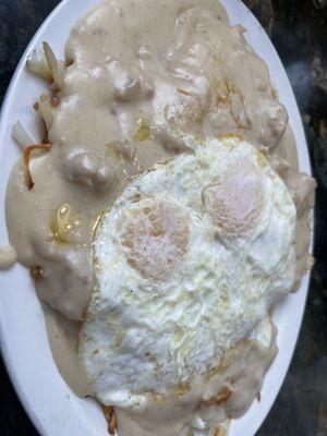 Half and half biscuits and gravy and hash browns and gravy with two eggs over medium.