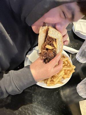 Son enjoying his Bacon Wrapped Pork Dog with extra crispy fries. Topped with BBQ pulled pork