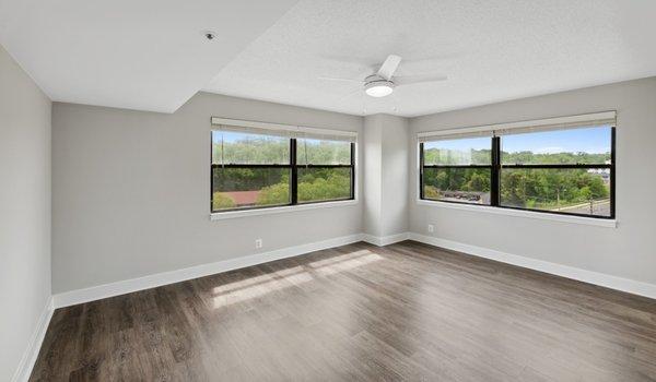 Spacious bedroom with natural lighting and wood flooring throughout