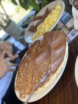 Golden pancake, scrambled eggs and bacon