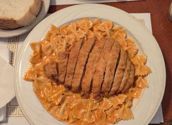 Bowtie pasta with tomato cream sauce and chicken cutlet.