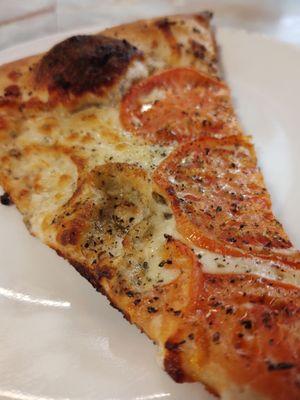 White pizza slice as it comes, with tomatoes and seasoning.