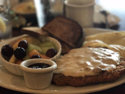 country fried chicken + gravy. over medium egg. toasted wheat bread w/ jam. fruit.