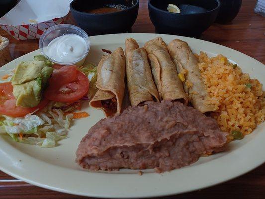 Flautas de pollo con arroz y frijoles.