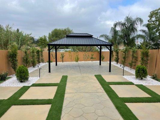 A new hardscape patio with artificial grass and a fruit tree orchard (in the back). An example of a low water, low maintenance landscape.