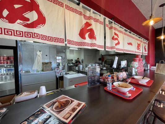 See through kitchen with a ramen bar.