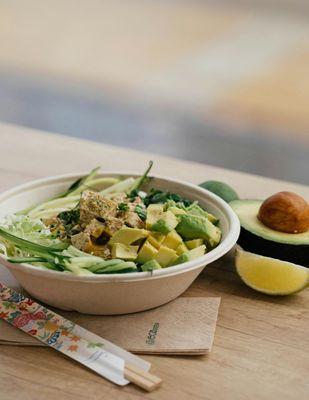 Bowl of fresh bowl with avocado, and other ingredients from Gourmondo, served with chopsticks and a lime wedge on the side.