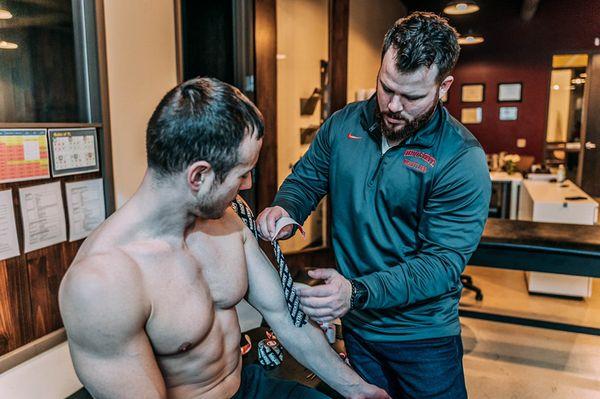 Dr. Kelly applying RockTape to an athlete's shoulder.