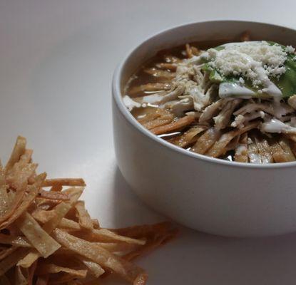 TRADITIONAL FRESHLY MADE TORTILLA SOUP PREPARED WITH CHICKEN, AVOCADO, COTIJA CHEESE, SOUR CREAM, LIME