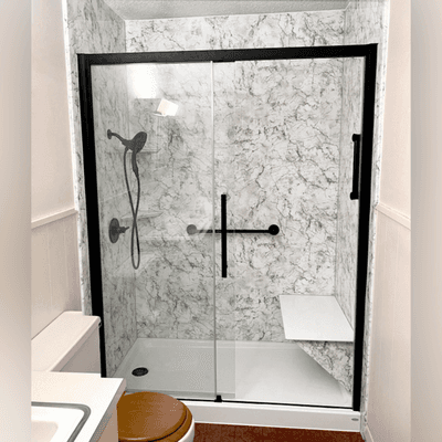 Grey and white walk-in shower renovation in style "Midnight Storm." This beautiful shower was customized to include a bench and grab bars.