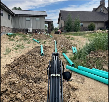 Installing large drainage pipe from downspouts to mitigate water off of property.