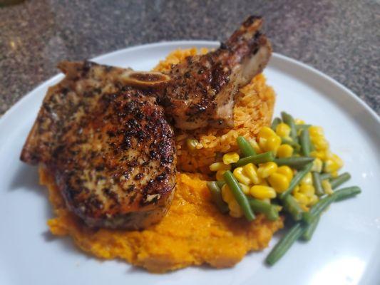 Roasted butternut squash puree, a thick cut pan seared pork chop, and mixed vegetables