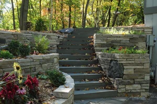 natural stone retaining wall separating upper and lower driveways, bluestone steps with a thermal finish