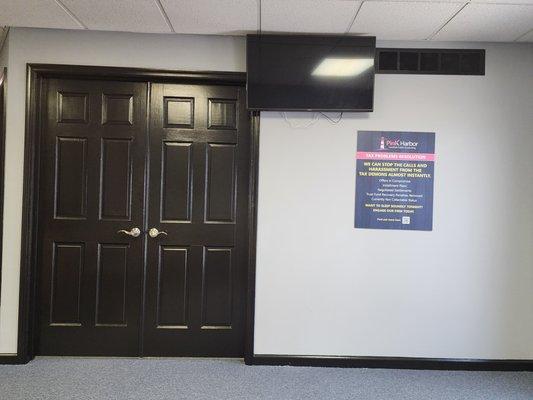 View of main lobby office doors with TV and sign at Pink Harbor, CPA