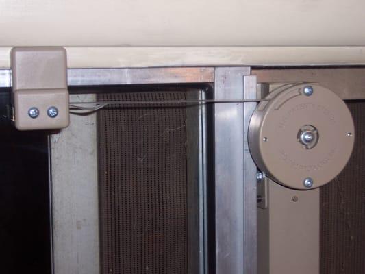 Close-up of strap actuated door closer mounted to left-handed sliding glass door