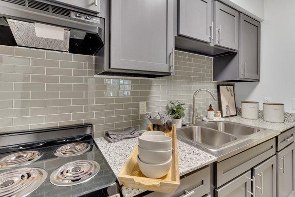 Kitchen with designer grey cabinetry and tile backsplash.