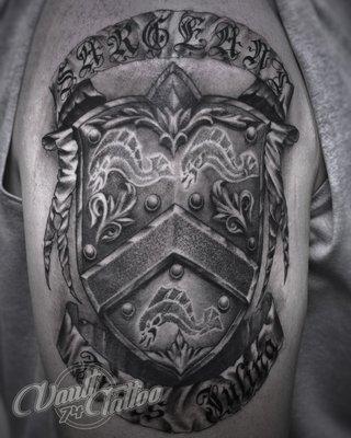 Best family crest tattoo design done on the upper arm in black and grey