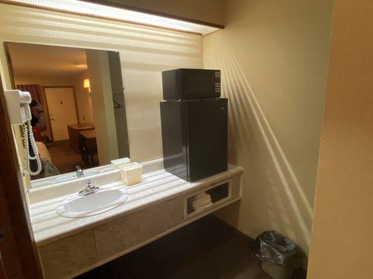 Mini refrigerator and microwave on the sink