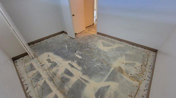 Bedroom floor after pulling up old carpet, underlayment, and tack strips