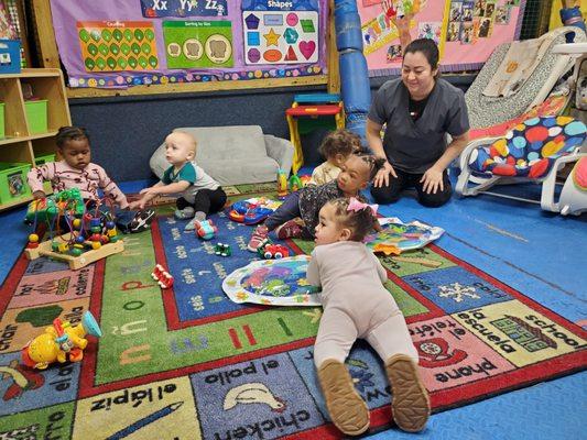 Infants are enjoying some belly time with water play mats and some infant toys.