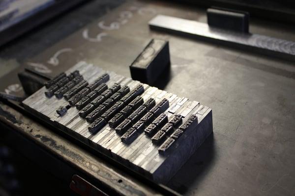 Arranging type letters to be inked and pressed onto a sheet of paper