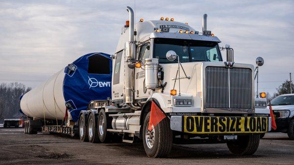 Windmill tower sections on stretch trailers.