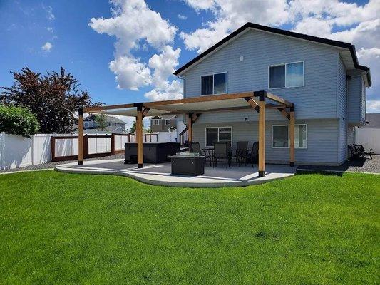 Concrete patio extension with pergola, fire pit area, and hot tub.