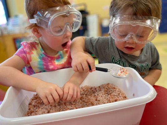 Two's exploring salts in a sensory bin