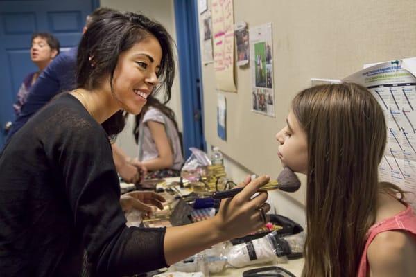 An Estee Lauder makeup artist preps a Usdan Fashion Design student to be photographed in her own design on "Fashion Design Day."