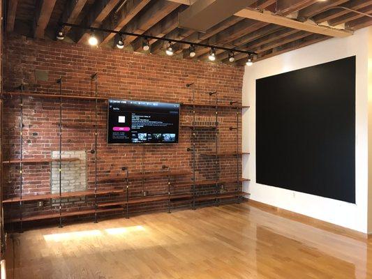 Custom iron pipe shelving with stained wood, 75" TV and magnetic chalkboard wall. Designed and installed.