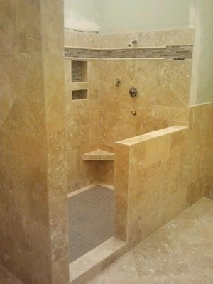 Custom bathroom with travertine and Glass accent strip, also glass accent in the nitch