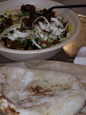 Bowl of chicken and steak, hummus, yellow rice, tomato/cucumber topping, grilled onion and basil with garlic & jalapenos sauce; side of pita