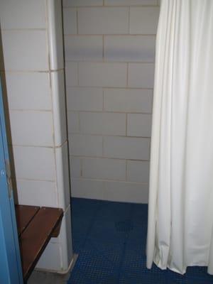 Women's shower with door, dry bench area and private curtained shower.