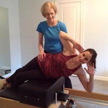 Mary assisting post-natal client with side sit-ups on the reformer.