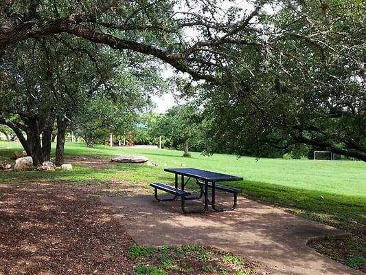 There are a few tables under the trees.