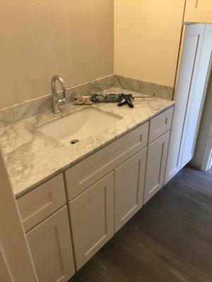 New white shaker bathroom cabinetry and quartz vanity top with sink and faucet.