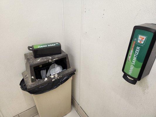 Soap dispenser laying on trash can.