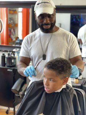 Master Barber Mr.John happily and patiently trimming my son Jaxson's hair.