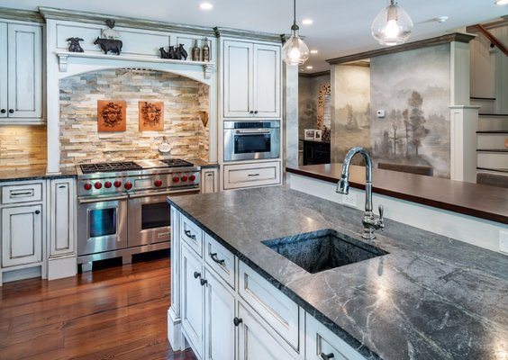 Kitchen cabinets have been antiqued and distressed for a time-worn look. A custom ethereal woodland mural has been painted on kitchen walls.