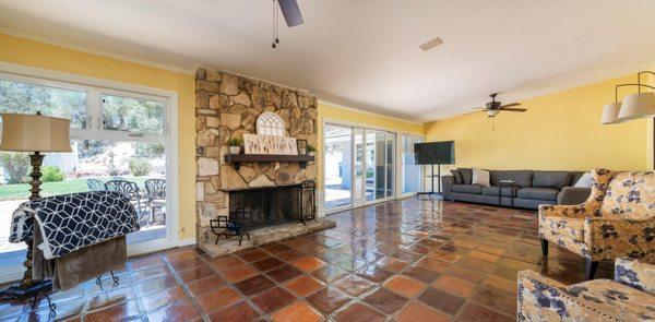 Spacious living room with cozy stone fireplace looking out the newer windows to the landscaped back yard.