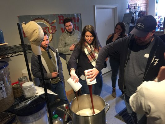 Birthday girl pouring the malt into the brew pot.