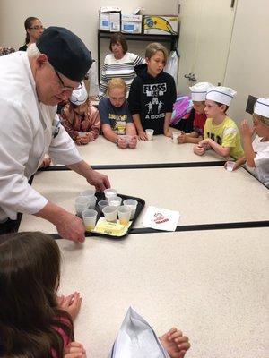 Chef Dan instructing the kids how to add the ingredients for cupcakes.