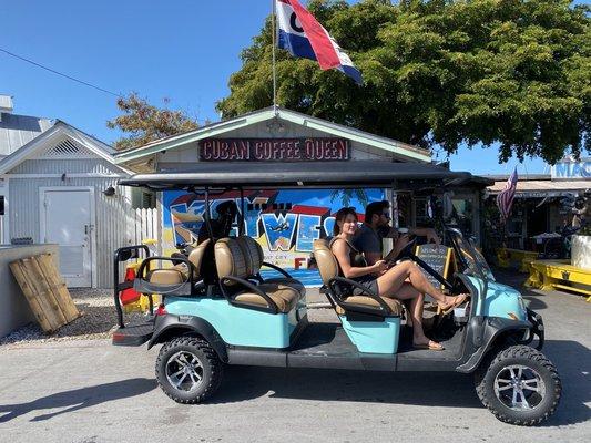 A mintys golf cart driving my a local art mural.