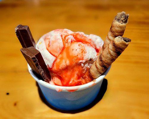 Strawberry ice cream with wafer stik, Kit Kat, and strawberry syrup.